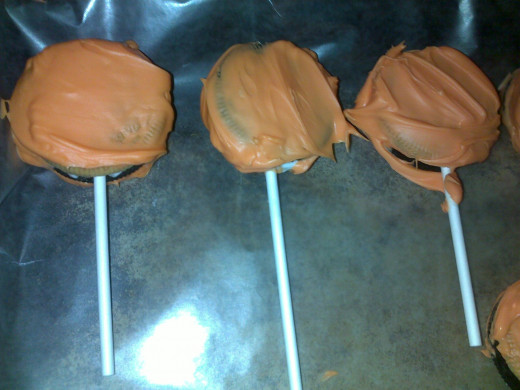 Coat the cookies with the melted chocolate. Be careful that the lollipop sticks don't come out!