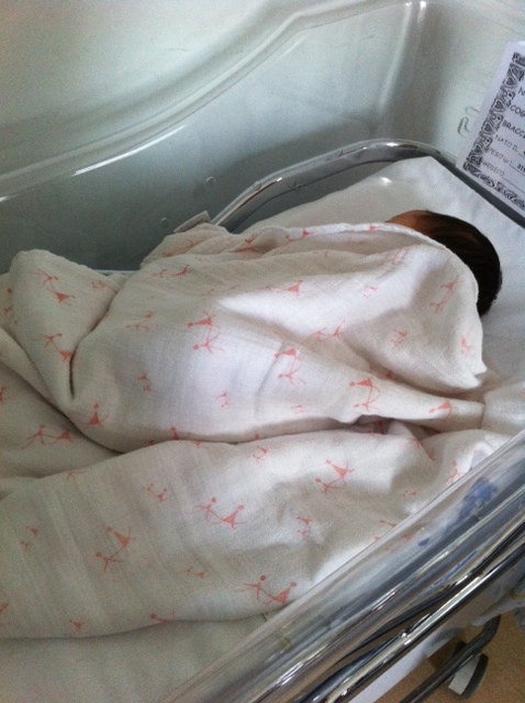 A newborn baby girl 1 day old in her crib in the hospital