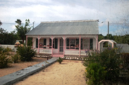 The Pink House. Said to be the second oldest house on the Grand Cayman Island. And, no it's not raining dust. The dusty effect to the right of the image is from taking this shot through the buse's window. Use image by permission only.