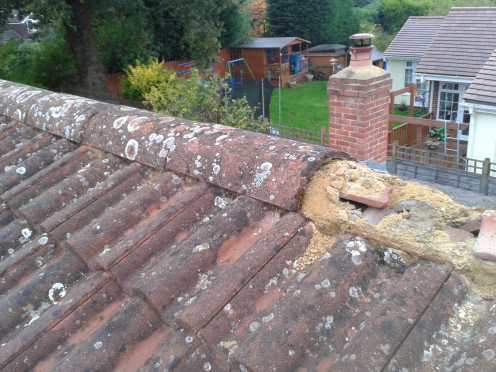 Photo shows ridge tiles being lifted and the existing cement removed.