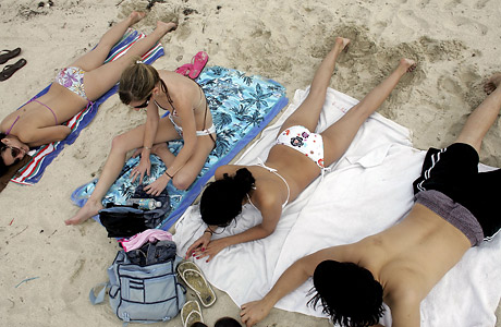 Young people sunbathing with bathing suits on in the sunlight.