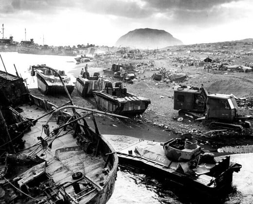 U.S. amtracs and other mobile vehicles lay smashed by Japanese mortar and artillery fire and/or caught in the black sand.  