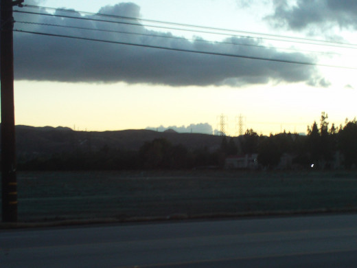 The view of the Box Springs Mountains in the distance with clouds floating above it.