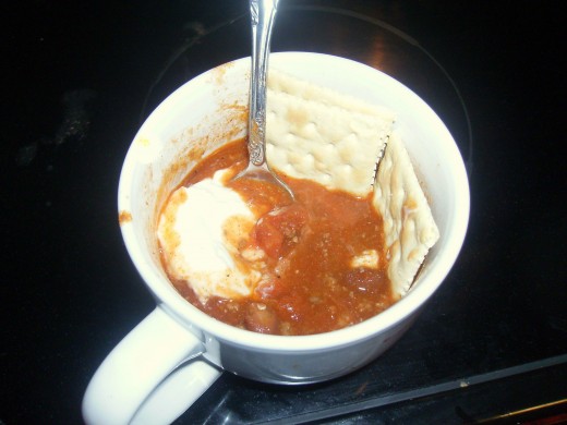 Half-eaten bowl of chili with crackers and sour cream