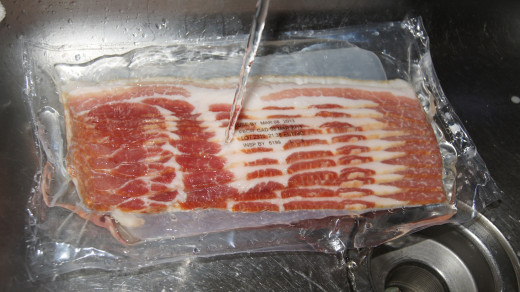 Run water over the frozen pack of bacon.