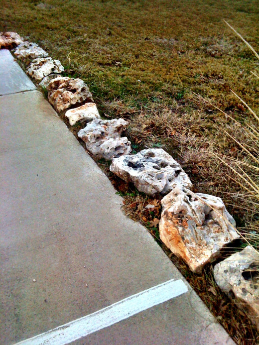 Stones line a green area along a parking lot keeping cars off the grass!