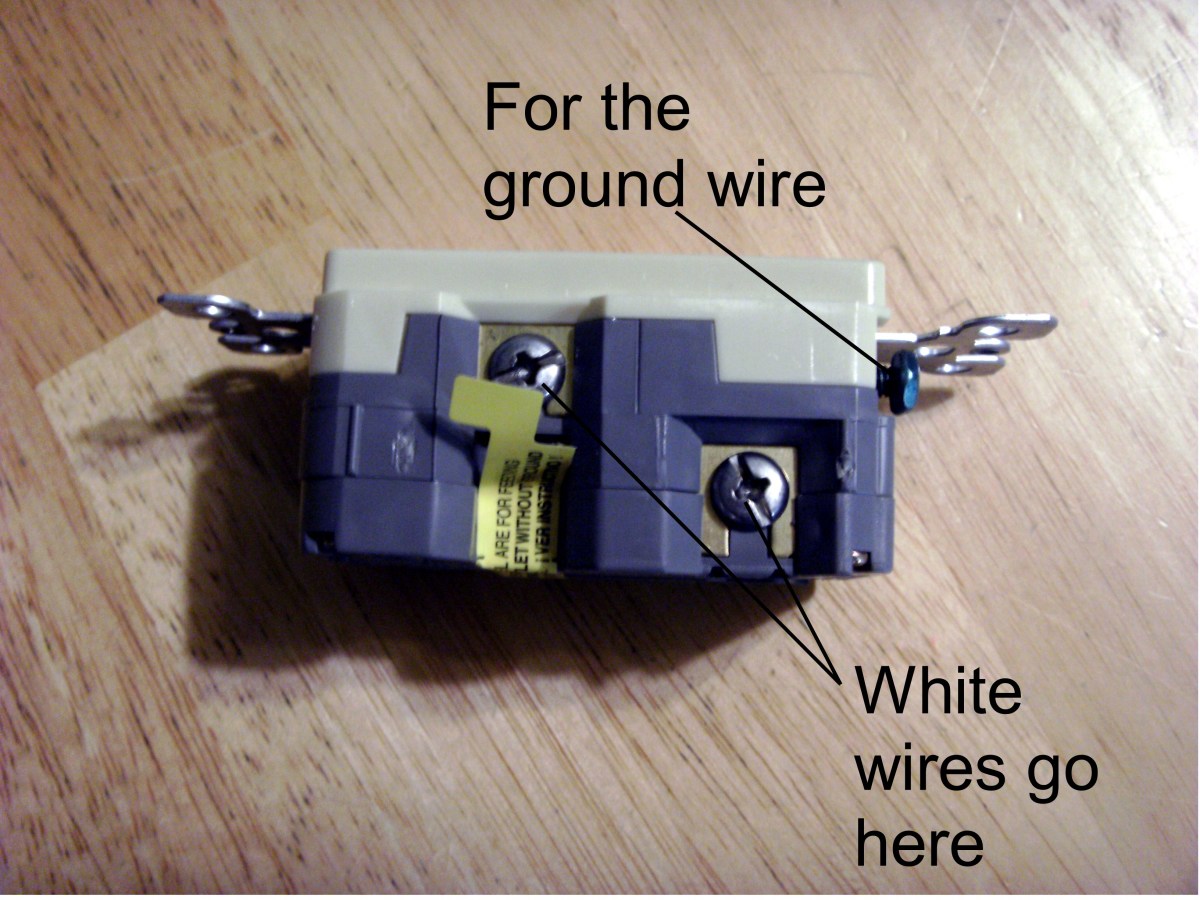 Connections for the neutral (white) wire and ground. Load wires go behind the tape.