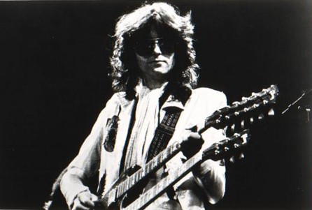 A promotional black and white image of Jimmy Page, performing with the rock group Led Zeppelin in 1977, officially issued by Swan Song Records.