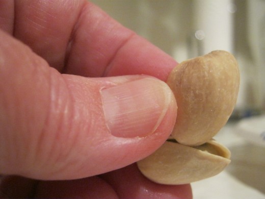 Pick up an empty one-half of a pistachio shell from the already eaten pistachio's and insert it into the partial crack in the difficult to open pistachio nut. 