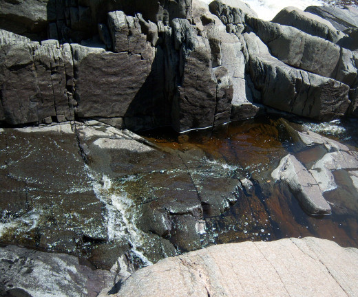 The water in the Baptism River in Minnesota is reddish due to the high iron content in the surrounding rocks. This landscape was shaped by glaciers thousands of years ago, and continues to be changed through erosion.