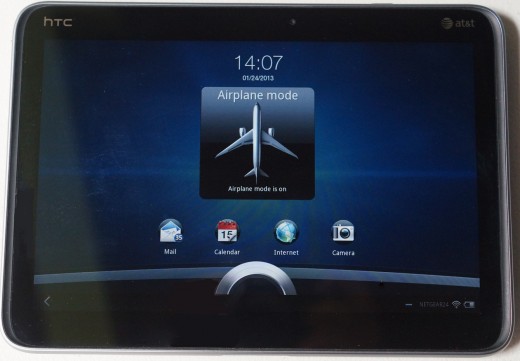 The display of the HTC Jetstream in Airplane Mode and locked.  Unlocking the screen is done by simply moving the bottom ring upwards.