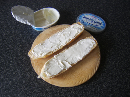 Cream cheese is spread on both halves of the sub roll