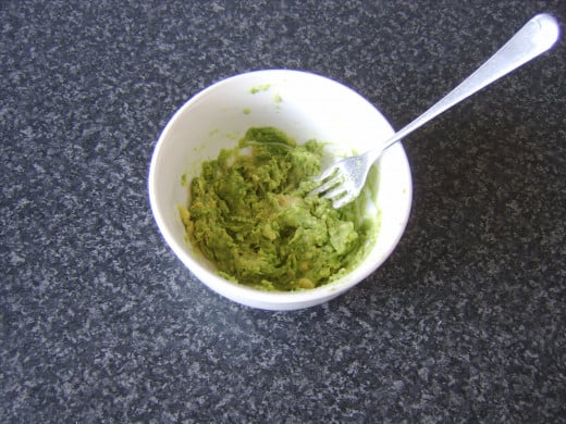 A fork is used to mash the avocado with salt and pepper