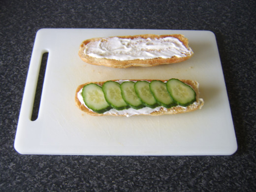 Cucumber slices are laid on top of the mayo on the bottom half of the sub