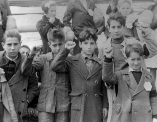 Republican children preparing to be evacuated in the aftermath of defeat to the Nationalists. Here, they are giving the Republican salute- a sign of defiance.