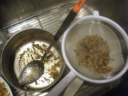 Pour the scrapings and water off through a strainer, and you see the pot will be pretty easy to finish cleaning.