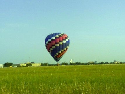 The hot air balloon hovered ABOVE the ground.