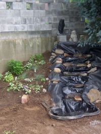 Liner is down and stones are placed around to hold liner and guide water down.