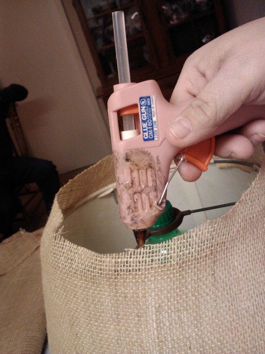 Firmly attach fabric with a hot glue gun.  Low temp glue will soften under the heat of a bulb.