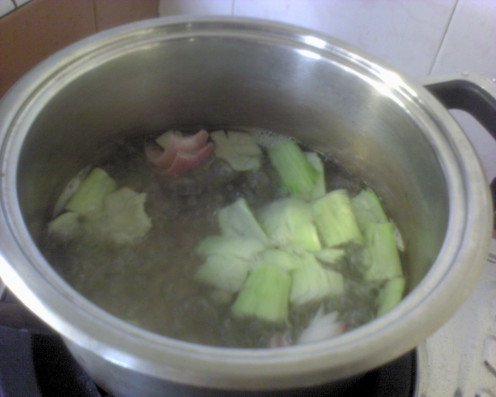 Add in the onion, smashed garlic and smashed stems into the boiling water