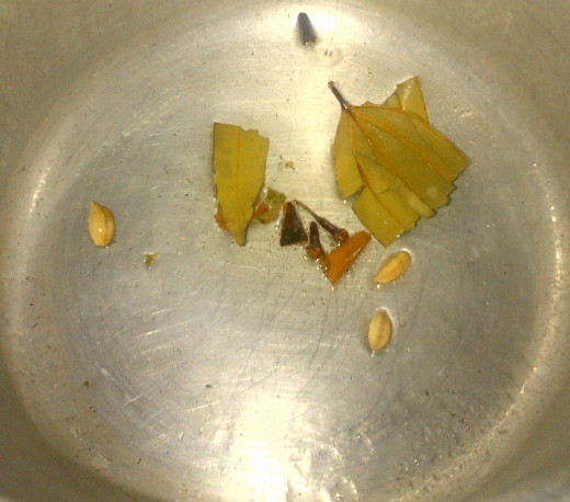 Tempering of cloves, cardamom, cinnamon, bay leaf in the oil