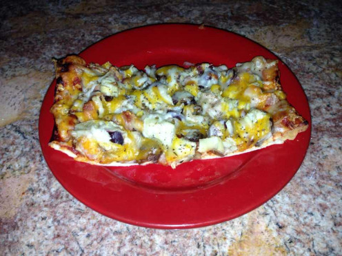 A slice of pizza - tomato paste, olives, marinated artichokes, Crimini mushrooms, apple smoked bacon and four cheeses (Mozzarella, Monterey Jack, Cheddar, Parmesan)