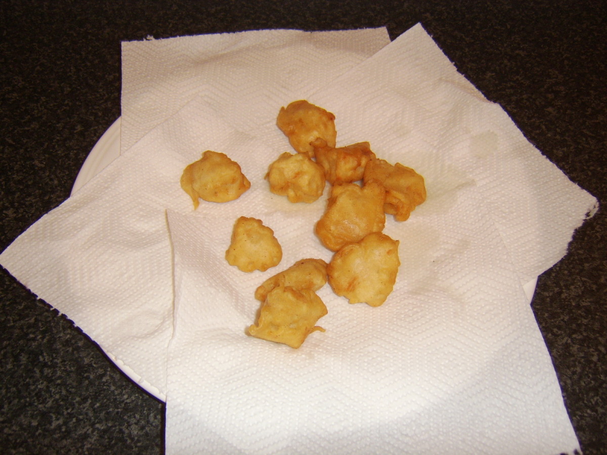 Deep fried chicken is drained on kitchen paper