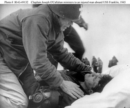 Fr. O'Callahan comforts a wounded sailor abourd the USS Franklin. The sailor would survive his injuries