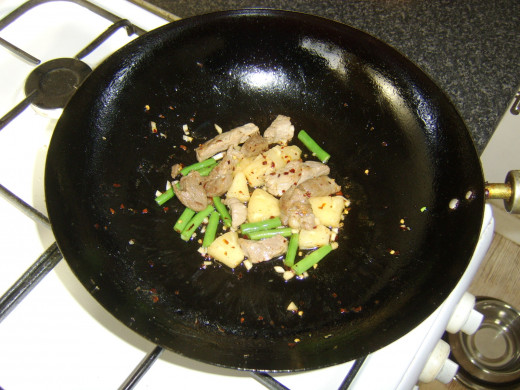 Pineapple, green beans and seasonings are added to stir fried pork