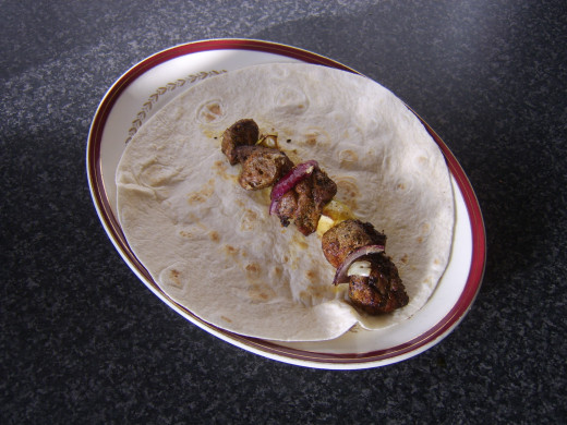 Shish kebab components are slid off the skewer on to a tortilla wrap