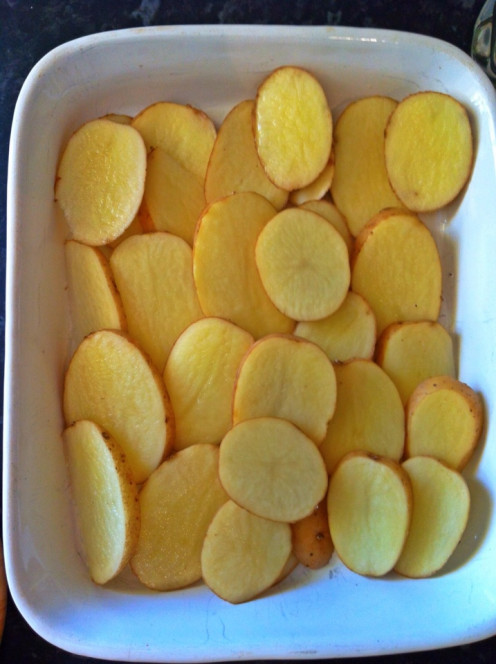 Line dish with sliced potatoes