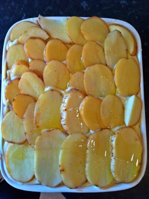 Top with sliced potatoes and drizzle with olive oil