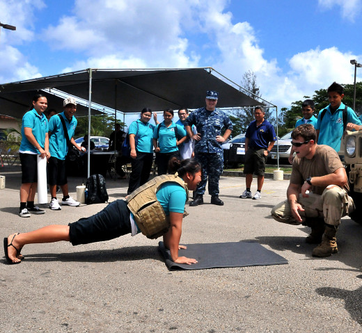 A high school student doing pushups with a weighted vest.
