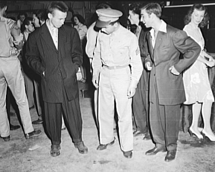 A serviceman appears to be intrigued by some youths in Zoot suits. 1942