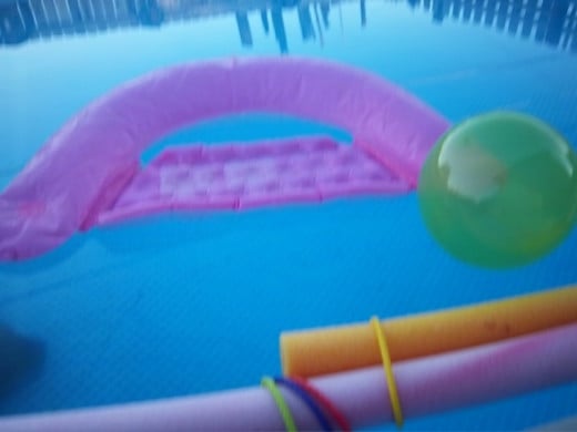 Image of an above ground pool with colorful flotation toys.