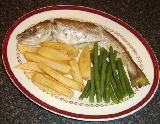 Chips and green beans are plated alongside whiting