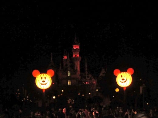 View of the castle from Main Street. The castle is decorated in orange and purple lights and is framed by two gigantic Mickey pumpkin heads! 