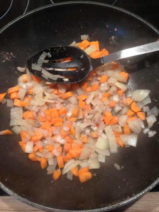 Adding the carrots to the frying onions