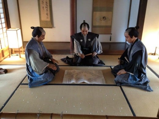 Replicas of feudal lords engaged in war strategy discussions in Honmaru Goten