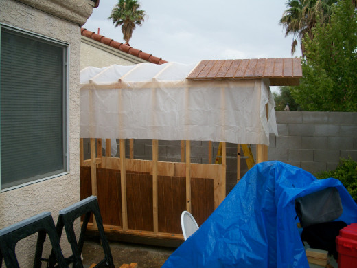 A sheet of plastic protects the wall frames and floor while the roof decking is installed. Most of the plastic remains underneath for extra moisture protection.