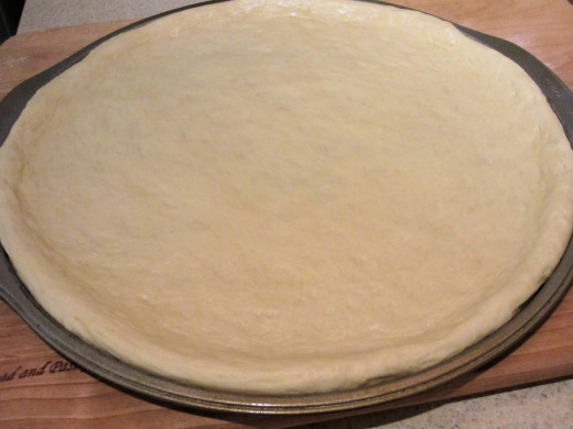 The pizza dough, once spread out, should be smooth and not pull back from the edges.