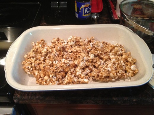 Mix the popcorn and peanuts in the candy mixture then place in greased baking dish