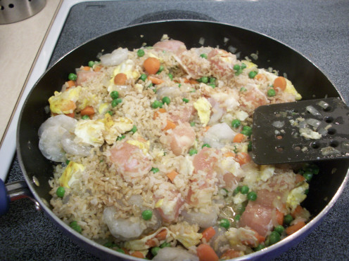 Add the cooked rice, chicken, shrimp, and sauces and stir together.  At this point you can push aside all ingredients to make room for the chicken and shrimp so they cook faster.