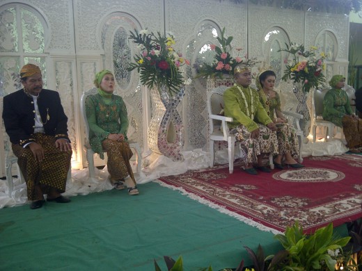 They sit on bridal chairs with parents take sitting positions next to their son/daughter in law.