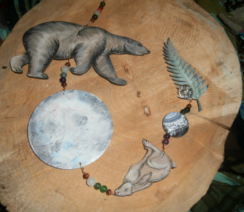 This spirit hanger features a bear, a large moon, a hare, a smaller moon and some bracken fern. 