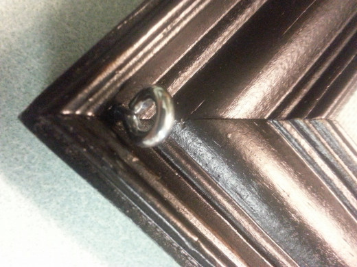 Eye bolt screwed into corner of picture frame.