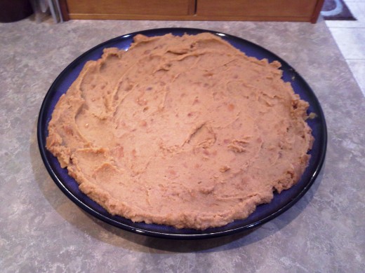 Step Two: Spread an entire can of refried beans onto the bottom of your platter, all the way to the edges