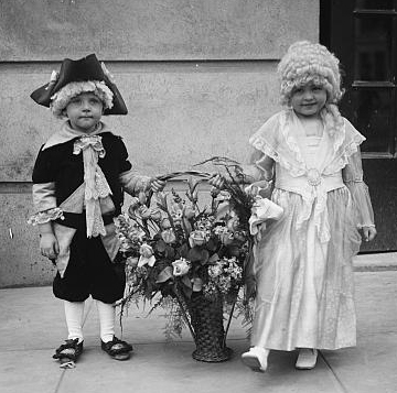 Children dressed in colonial costumes with basket of flowers 