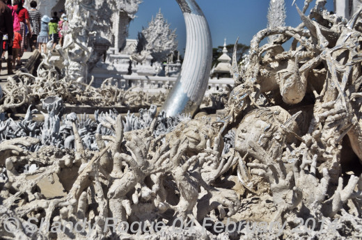 Spirits reaching out in their desperation to escape from hell. And, in the middle of it all is a lovely face and a monkey's head. Could this be the punishment for vanity? Location: Wat Rong Khun (The White Temple)