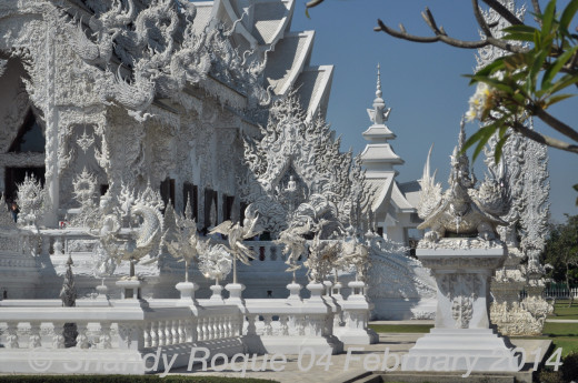 The prayer hall is surrounded by mystical creatures. On each side of the prayer hall are images of the Buddha. Location: Wat Rong Khun (The White Temple)